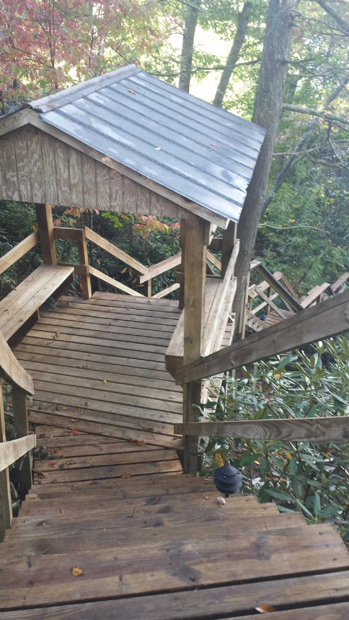 Metal roofed shelter over wooden steps on a wooded walkway — Skylight Repair & Installation work by our crew in Flushing