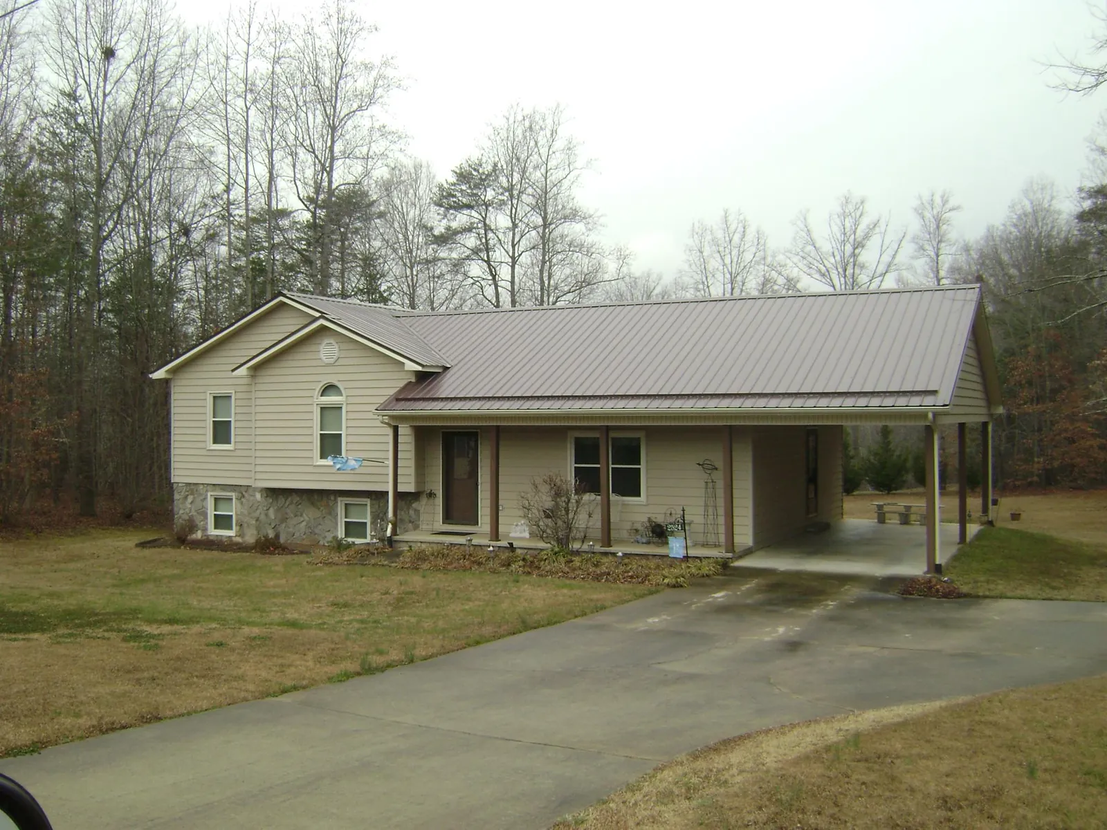 Brown metal roof on a tan split level home with an attached carport in Flushing